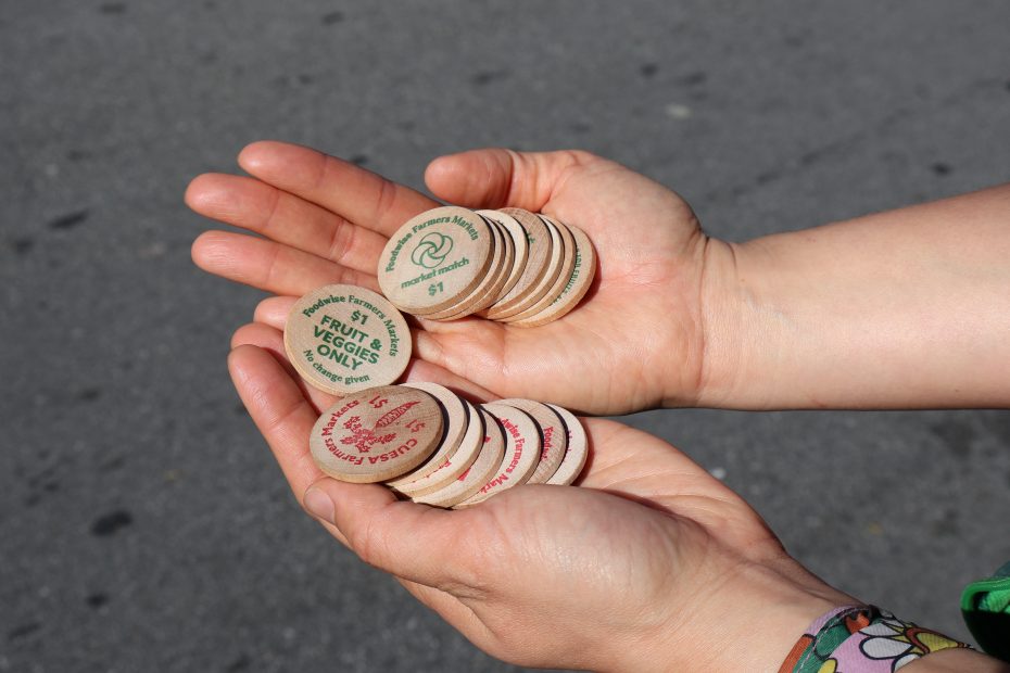 Two hands holding assorted wooden tokens with various inscriptions, outdoors in daylight.