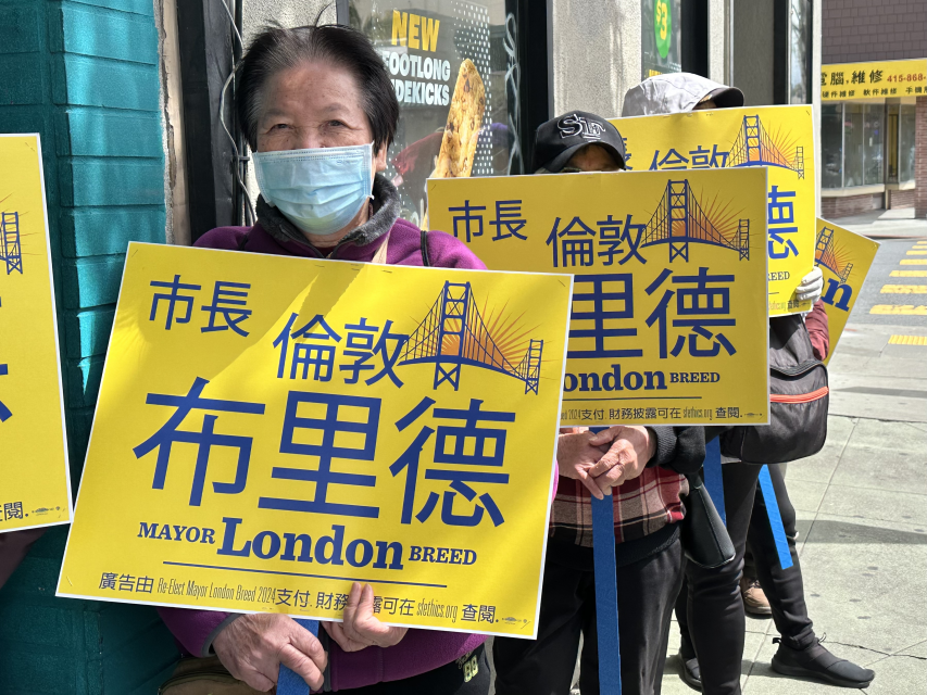 Fay Yu Lou stands with a yellow campaign sign reading "London Breed"