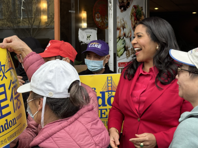 Mayor London Breed smiling at a yellow campaign sign
