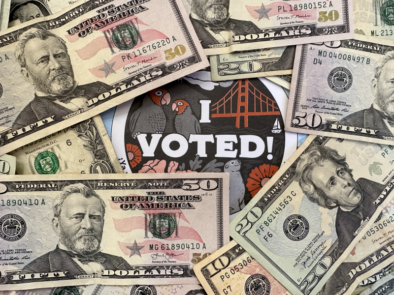 Dollar bills in front of an "I voted!" message. For San Francisco election coverage.