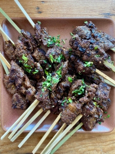Skewered grilled meat garnished with chopped herbs on a plate.