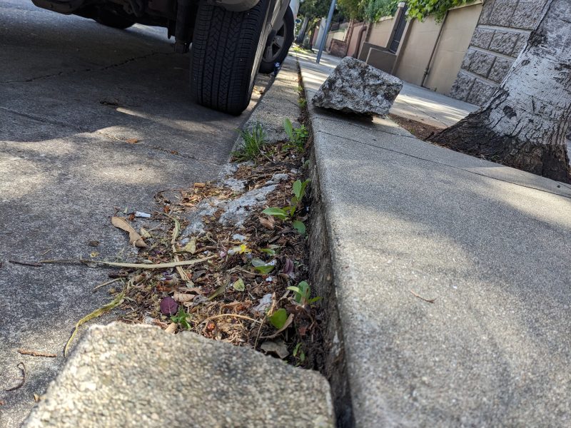 A piece of broken concrete on the pavement next to a parked vehicle.