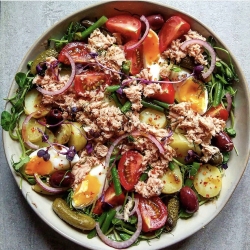 A bowl of tuna salad with assorted vegetables and a sprinkling of herbs.