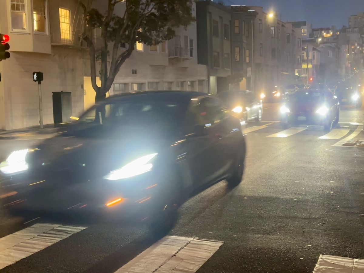 a grey Tesla driving through the street