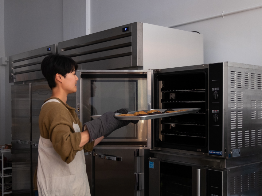 a woman pulls a bake sheet out of the oven