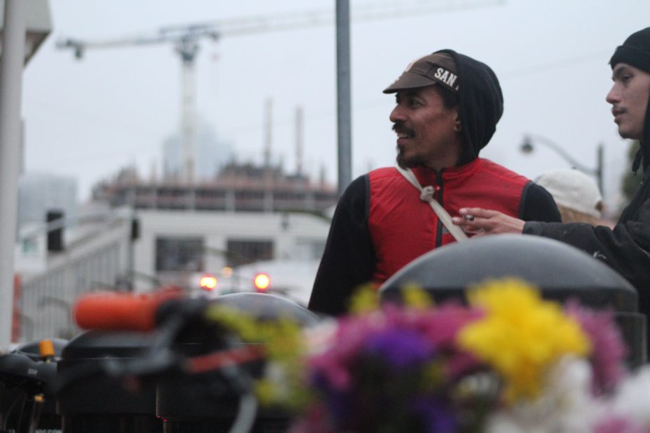 Luis Cisneros and Angel Hancock look at other volunteers place flowers at the intersection of 4th and King streets on Wednesday May 15, 2024. Photo by Oscar Palma.