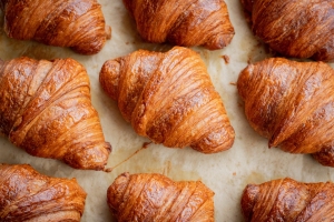 Close-up image of freshly baked, golden-brown croissants arranged on parchment paper.