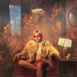 Woman in red blindfold and fur coat seated on a plush chair in a smoky, dimly-lit room with vintage decor.