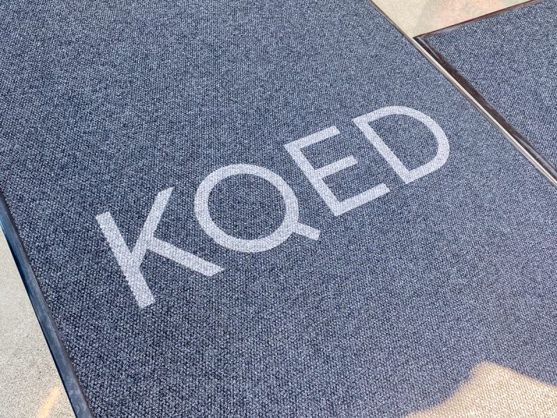 A gray doormat with the iconic letters "KQED" printed in crisp white.