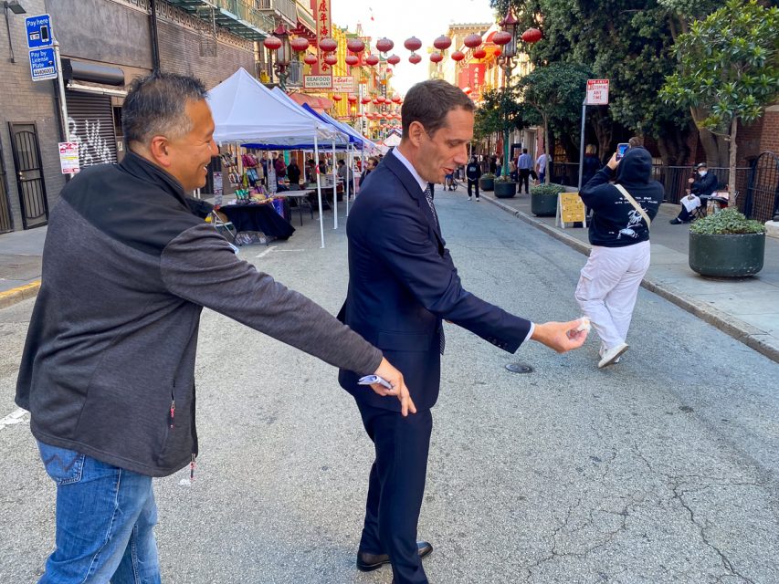 Two men practicing on a street decorated with lanterns, with a third person in the background.