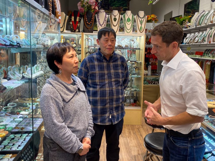 Two jewelry store employee and a caucasian male in a white shirt talking in the store.