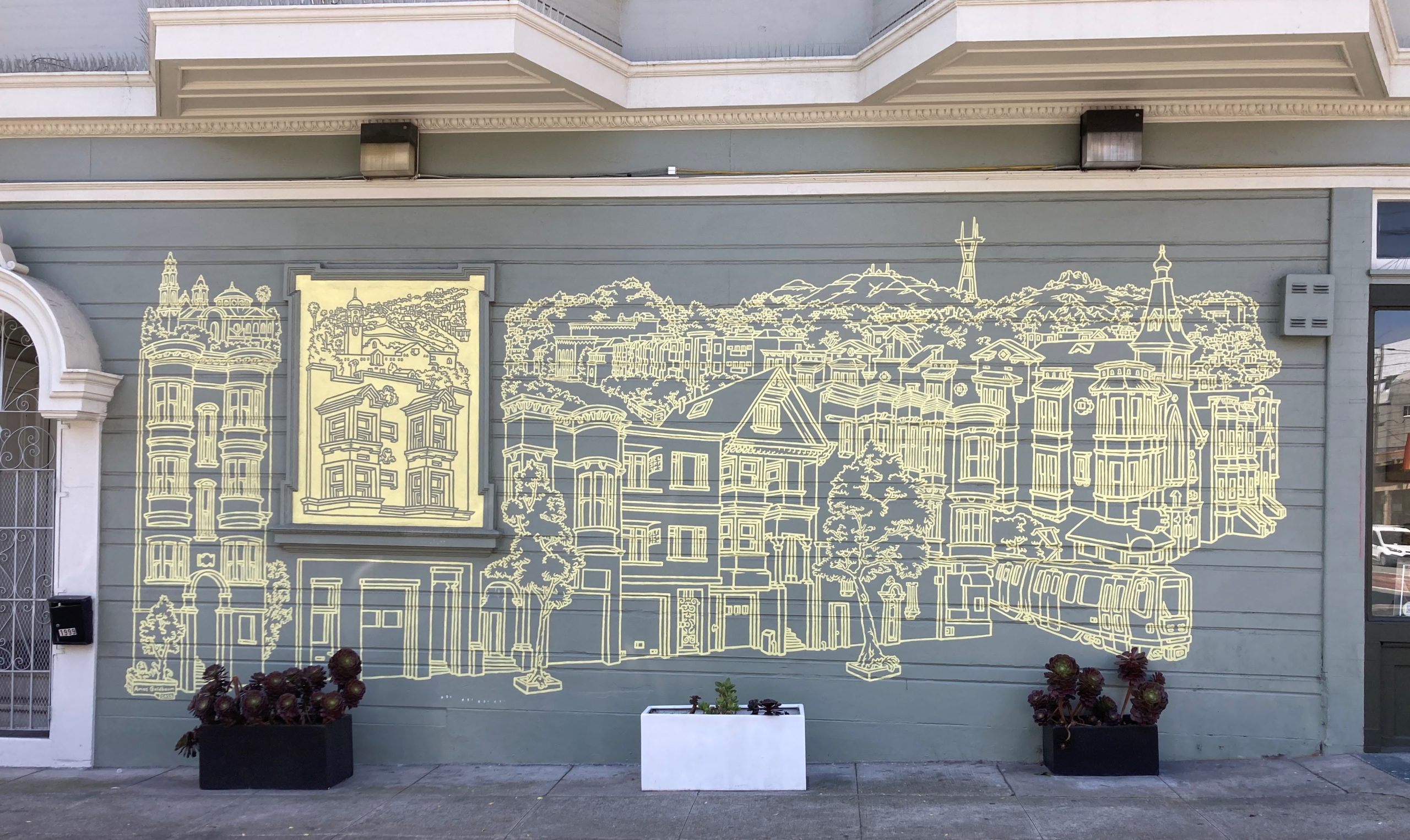 A wall mural with a yellow line drawing of a cityscape featuring detailed buildings, trees, and a prominent tower. Plants in black and white planters are placed in front.