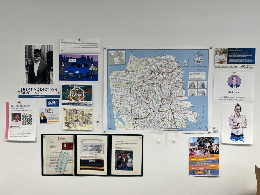 A wall display with a city map, various flyers, photos, and notices including information on addiction, voting, events, and community programs.