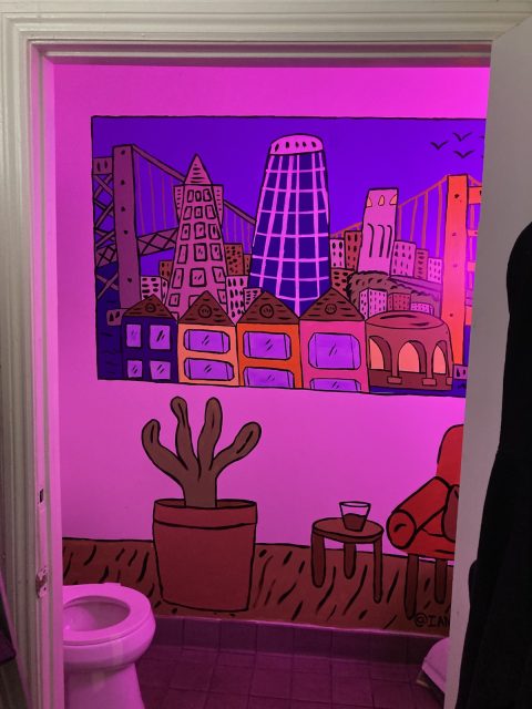 A mural depicting a window view of San Francisco, a chair and a houseplant, basked in neon pink light, next to a toilet.