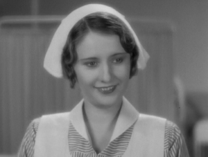 A woman in a nurse's uniform smiles. The image is in black and white.