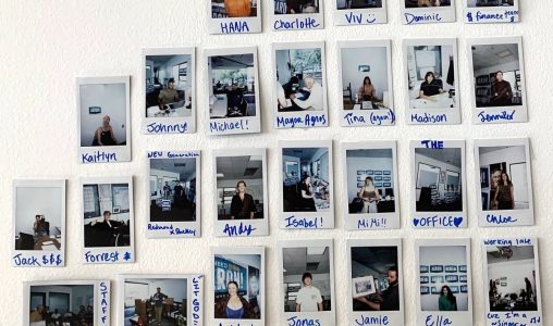 Wall display of Polaroid photos featuring various individuals in office settings, each labeled with handwritten names.