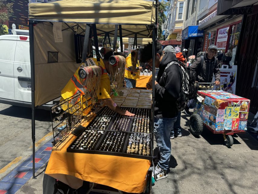 A permitted vendor tries to finish a sale during the first day of a pilot program that allows 10 merchants to go back to Mission Street on Friday June 21, 2024. Photo by Oscar Palma
