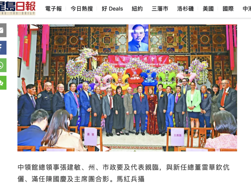 A group of people posing for a photo in front of a colorful stage with a portrait above them. The setting features ornate decorations and several vibrant, costumed figures.