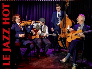 Four musicians play jazz instruments on stage. The sign reads "Le Jazz Hot." One plays a violin, one a guitar, one an upright bass, and another sits with a guitar. All are dressed in formal attire.