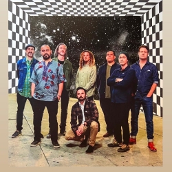 A group of eight people, casually dressed, pose for a photo against a backdrop featuring a checkerboard pattern transitioning into a starry sky.