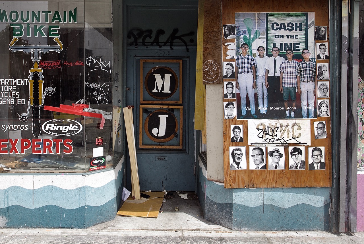 A storefront with displayed signs, including "Mountain Bike Experts" and a poster showing multiple headshots under the text "Cash on the Line." The entrance area is cluttered.
