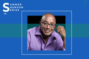 Man in a purple shirt sits smiling with one arm resting on a table. Blue background with the text "SUMMER HENSON SERIES" in the top left corner.