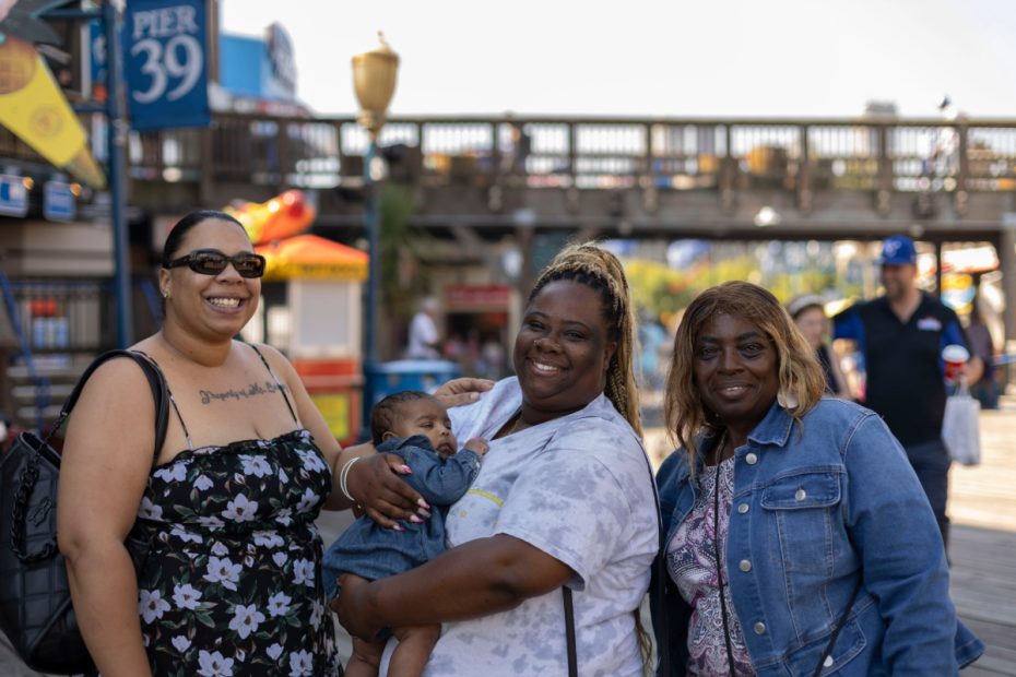 Three black women, one holding a baby, at Pier 39, just before July 4.