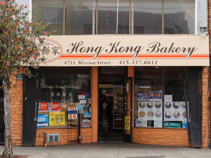 金城餅家的店面，有英文和中文招牌，位於 Mission Street 4711 號。入口門是開著的，窗戶上展示著各種標誌。