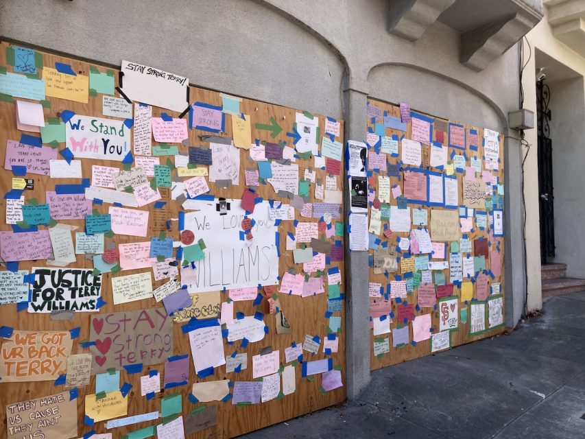 A wall covered with various colorful notes, messages, and posters expressing support and solidarity. Signs include phrases like "We Stand With You" and "Stay Strong.