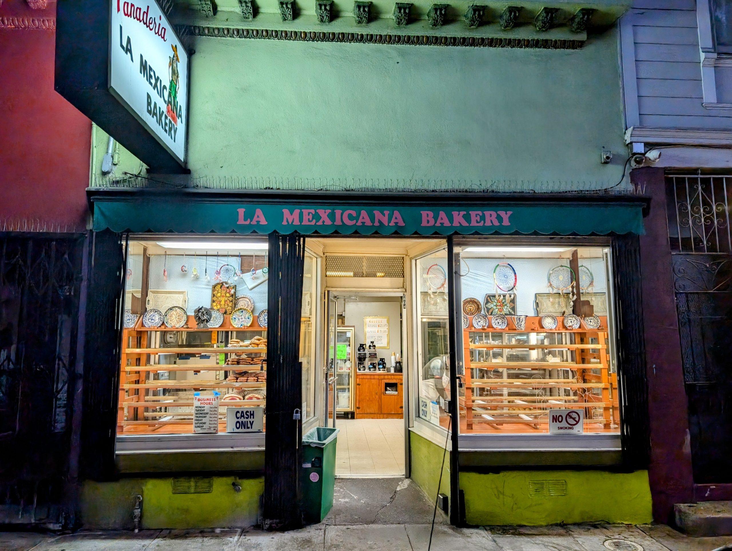A brightly lit storefront labeled "La Mexicana Bakery" with pastries displayed in the window and a "Cash Only" sign by the door.