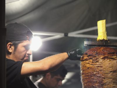 Daniel Contreras slicing some meat off a trompo to make al pastor tacos at "El gran trompo regio" on Saturday Aug. 10, 2024. Photo by Oscar Palma.
