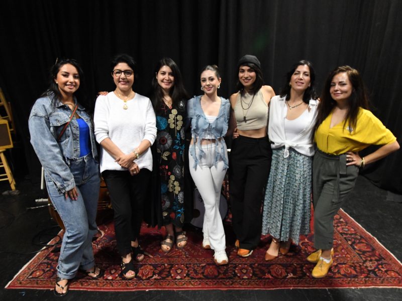a group of women from Middle Eastern countries pose smiling at a concert rehearsal