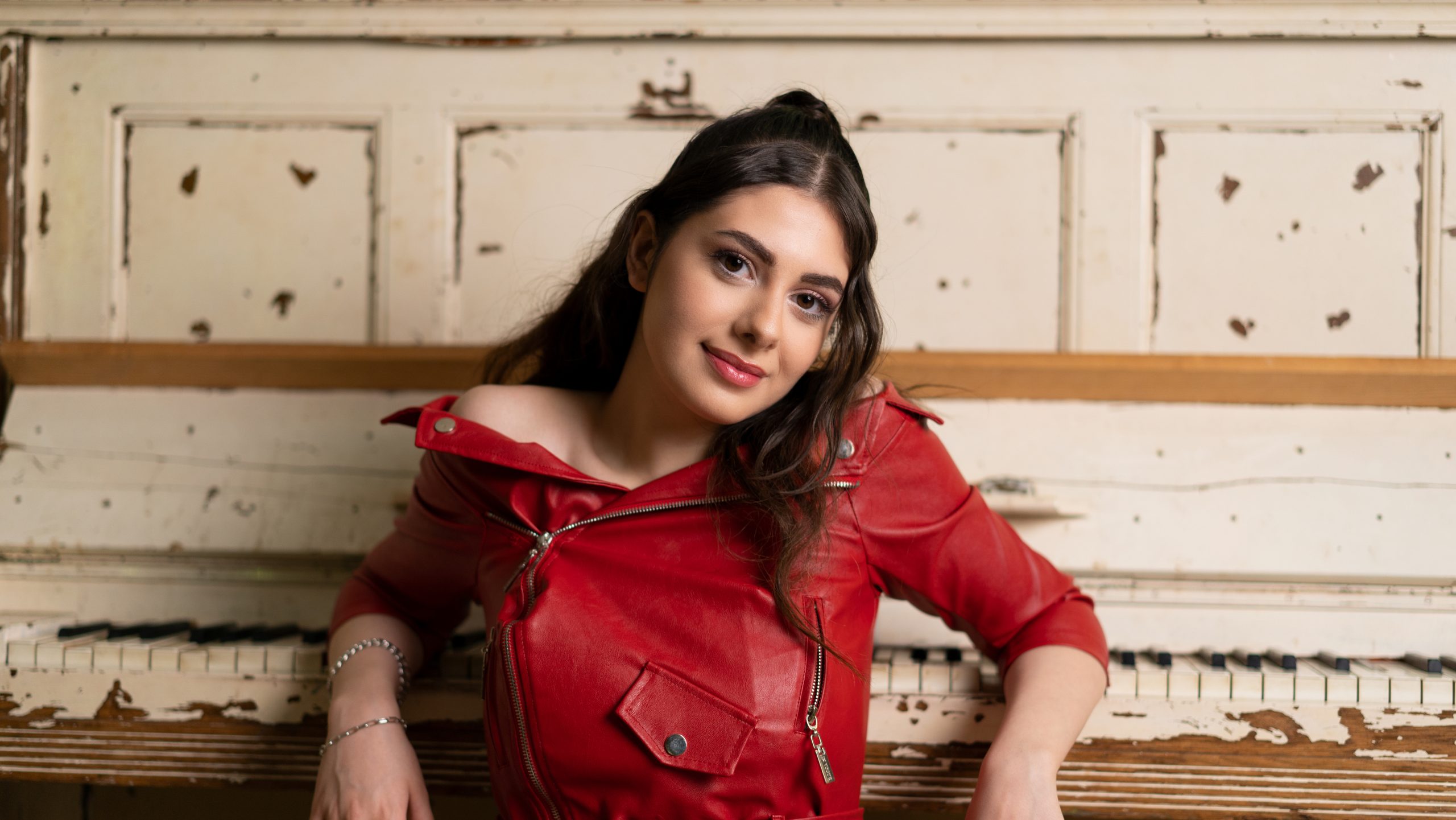 a young woman with black hair in a red top smiles in a portrait