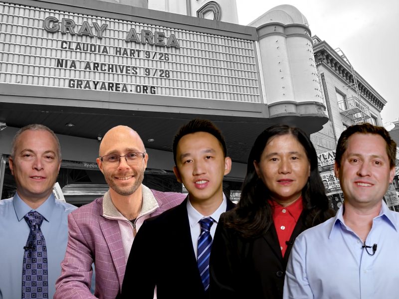 A group of five people standing in front of a marquee sign that reads "GRAY AREA" followed by event details, with a building in the background.