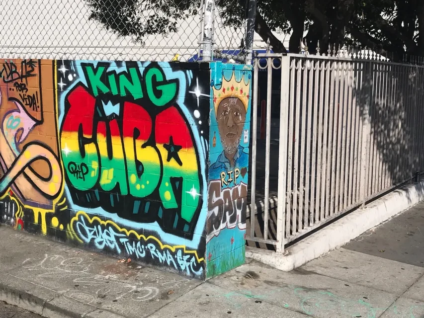 Colorful graffiti on a corner wall features "King Cuba" lettering and a portrait with a crown.