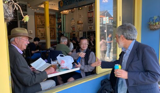 Three people engage at a café window: one inside reading a Peskin novel, another seated with a drink, and the third outside holding a can, leaning in for a handshake.