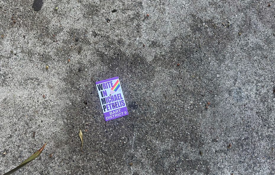 A "Write in Michael Petrelis BART District 9" campaign sticker adds a splash of color to the rough concrete surface, capturing the spirit of the SF election.