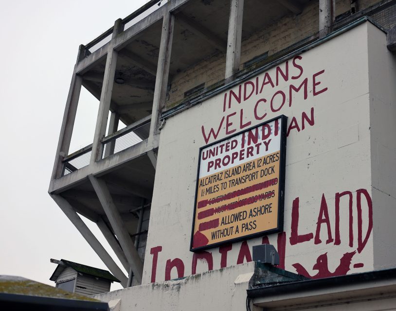Sign on a building reading "Indians Welcome, United Indian Property" with details about Alcatraz Island area and transport rules.