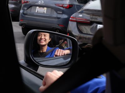 Woman in rearview mirror smiling at the camera