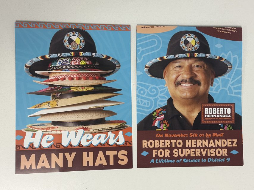 Campaign materials for Roberto Hernandez, featuring a stack of hats and a portrait, highlight his candidacy for Supervisor in the SF election. The text reads: "He Wears Many Hats," emphasizing his multifaceted expertise and commitment to serving the community.
