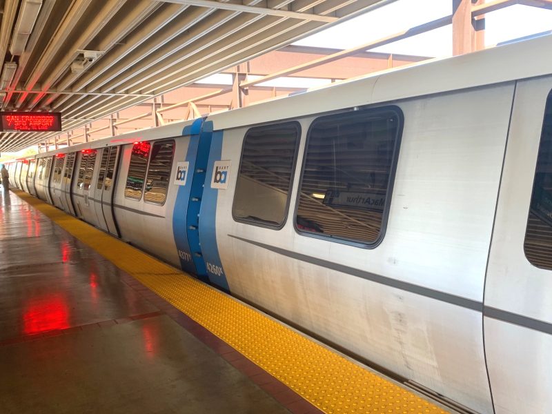 BART 列車停靠月台，上方顯示牌和安全警示帶清晰可見。