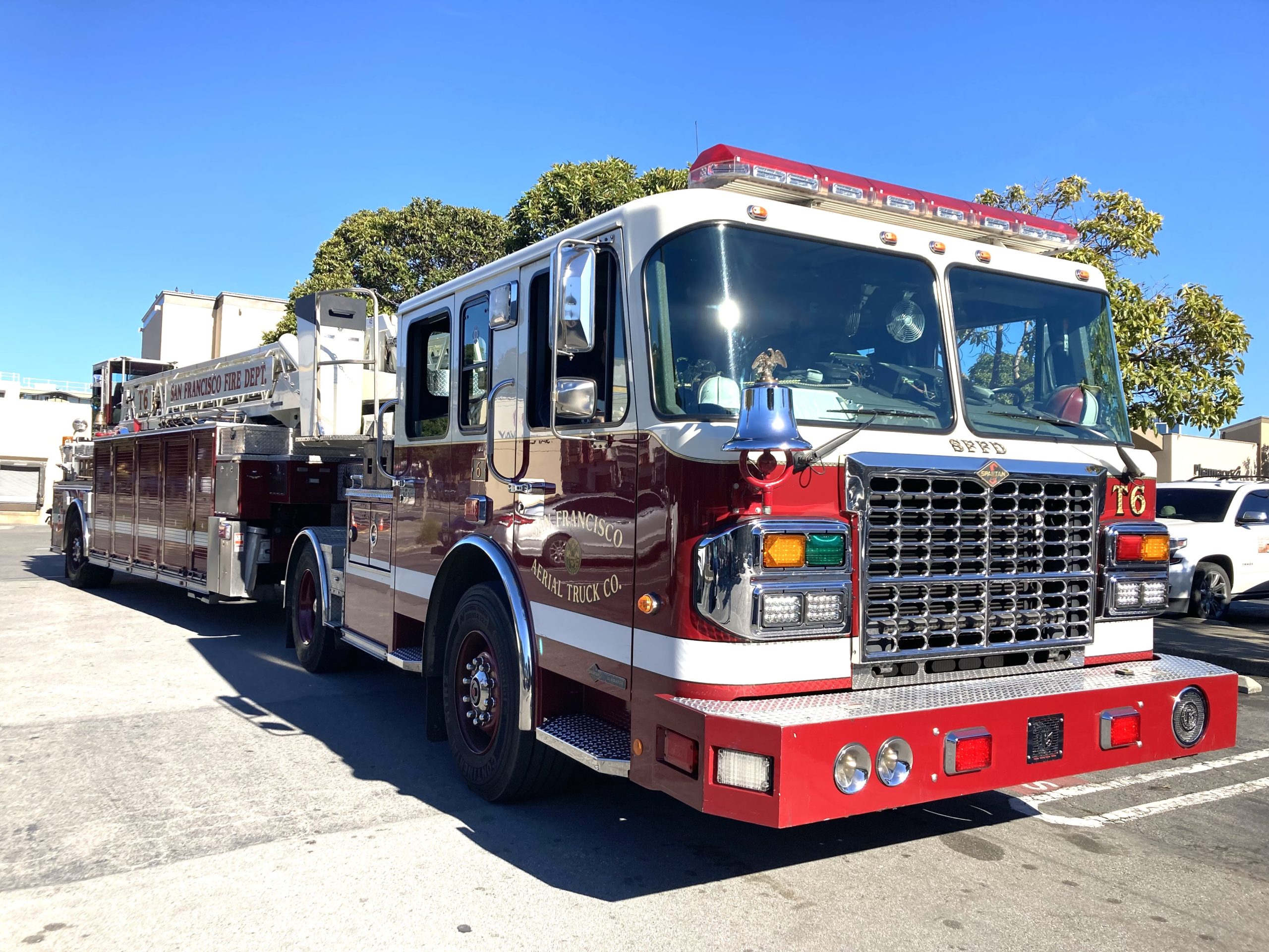 A red and white fire truck is parked on a street with trees and buildings in the background.