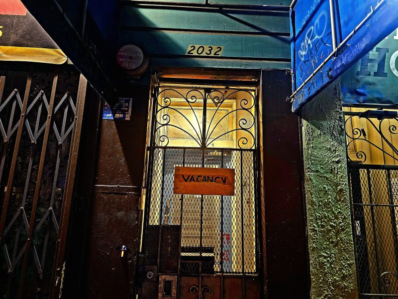 Dimly lit entrance of building 2032 with a metal gate and a "Vacancy" sign.