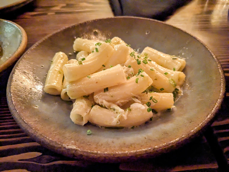 A plate of rigatoni pasta with a creamy sauce, garnished with chopped chives.