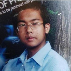 Young person wearing glasses and a blue collared shirt, looking at the camera.