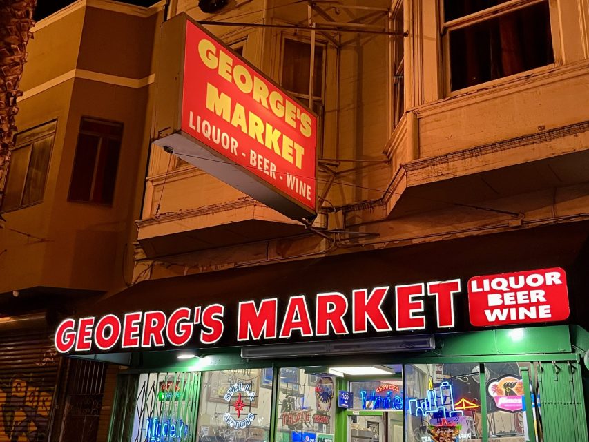 Nighttime view of George's Market exterior, with illuminated signs for liquor, beer, and wine.
