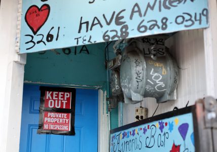 A blue door with a "Keep Out, Private Property, No Trespassing" sign. Graffiti and a heart design appear on the surrounding walls.