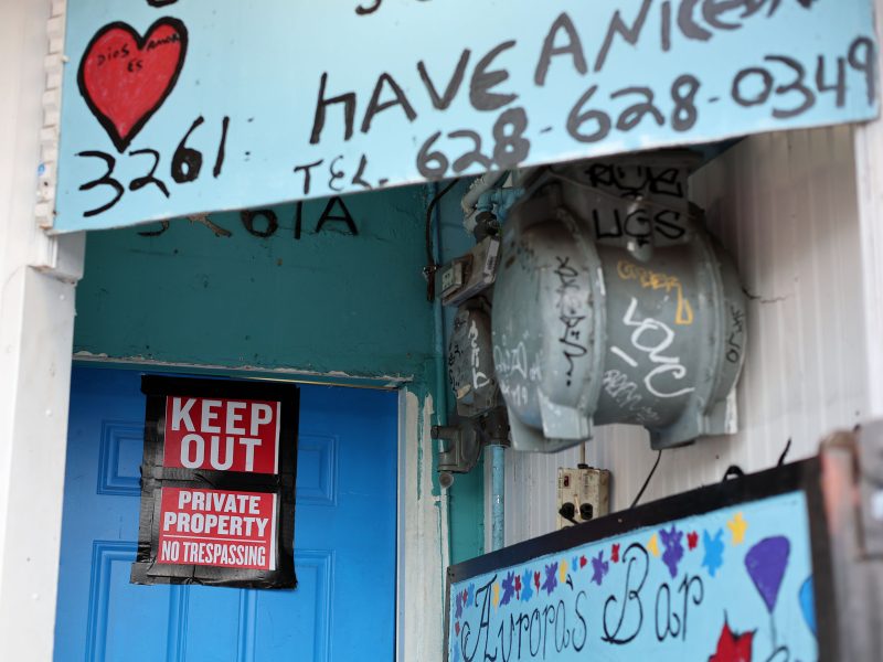 A blue door with a "Keep Out, Private Property, No Trespassing" sign. Graffiti and a heart design appear on the surrounding walls.