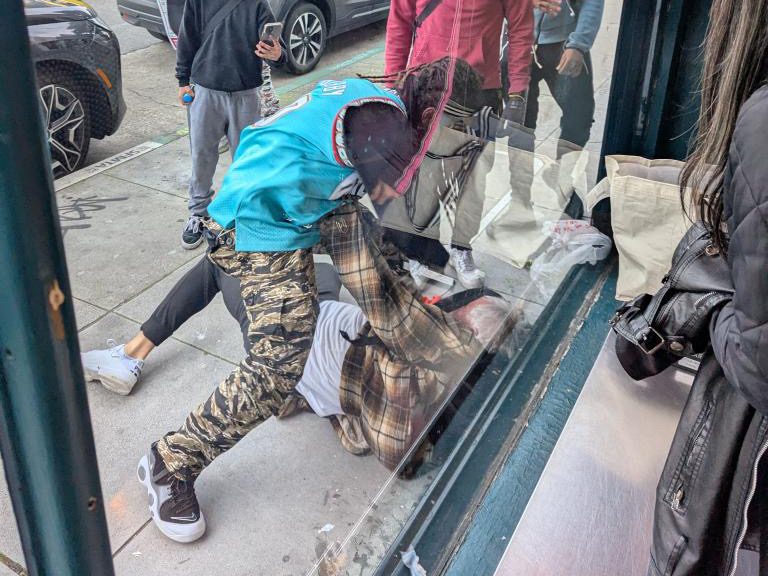 One of the two arrested man assaults an older man outside of Buffalo Exchange at 23rd and Valencia streets, on Feb. 16, 2025.