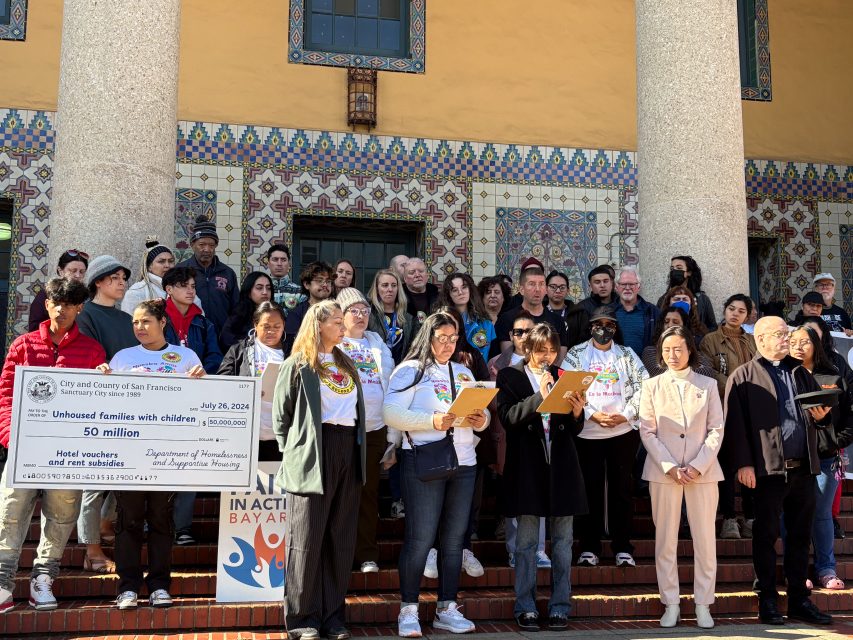 A group of people standing on the steps of a building, holding papers and documents, with a diverse range of expressions.